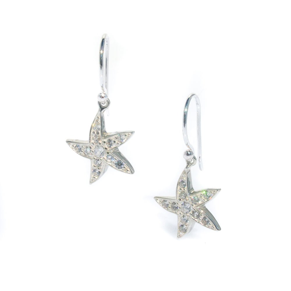 A pair of silver star-shaped earrings with cubic zirconia embedded within the design, attached to hooks for wear.